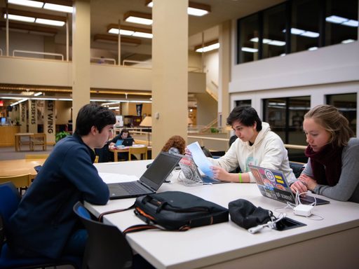 Three students with computers studying together
