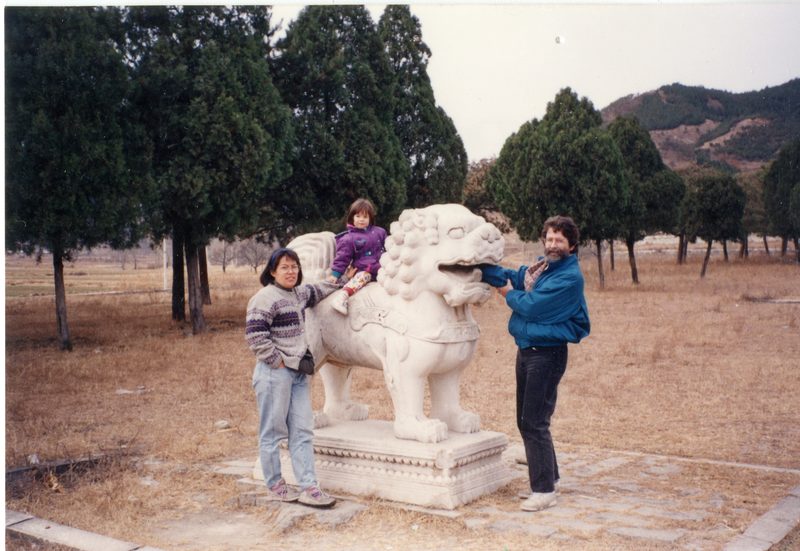 3 people posing with Chinese stone animal sculpture.