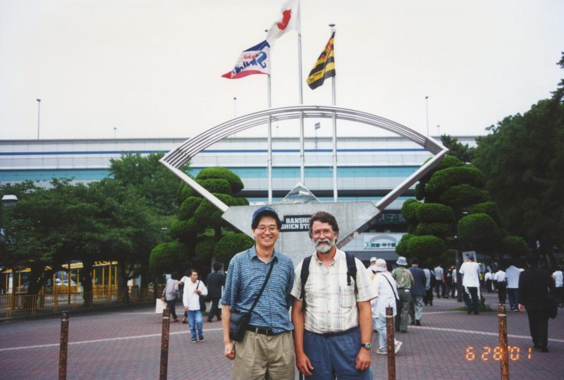 Two people posing outside the Hanshien Koshien Stadium