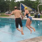 Two people jump into a pool
