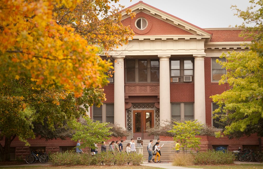 Students walk in front of a campus building in the fall