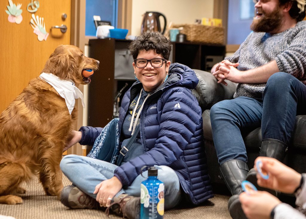 A student smiles with a dog