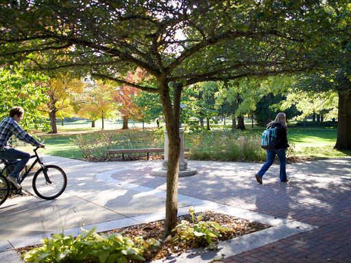 Students walk and bike through campus in autumn.