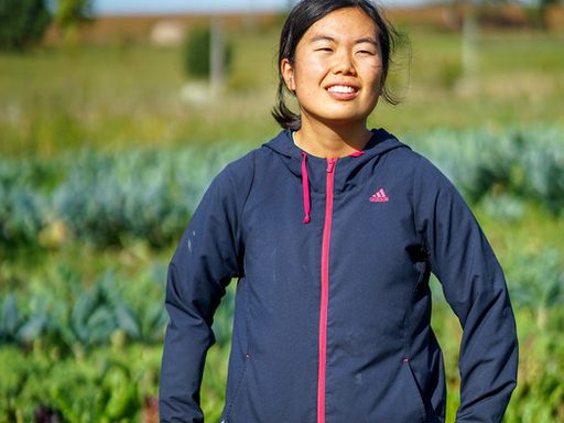 A student stands in a farm field and enjoys the sun.
