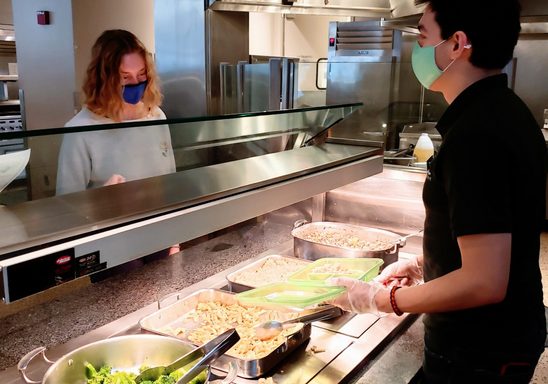 A Bon Appetit staff member dishes up a meal for a student