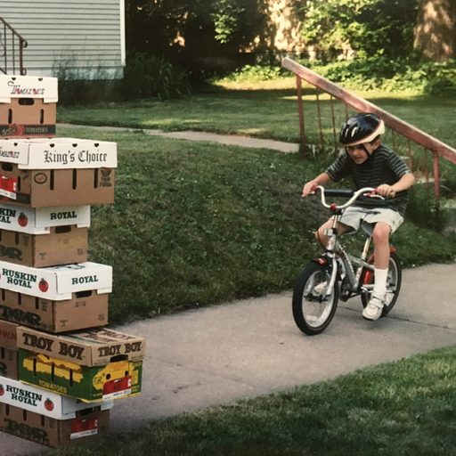 A boy rides a bike into a stack of boxes