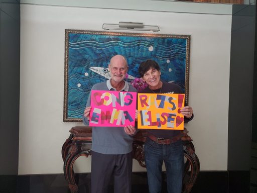 Two men hold a sign reading
