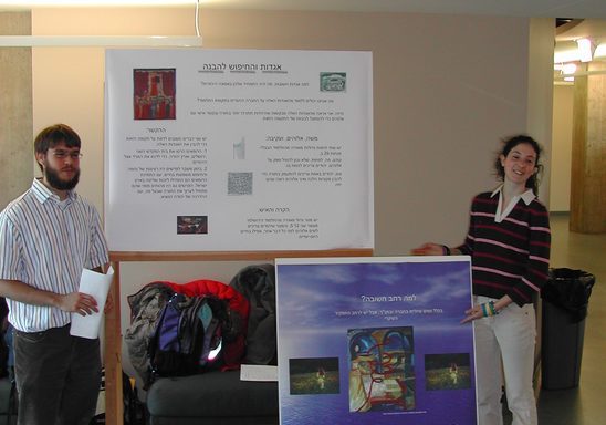 two students standing beside academic posters