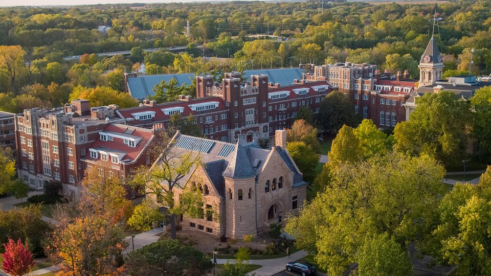 Aerial view of a college campus featuring buildings and treetops