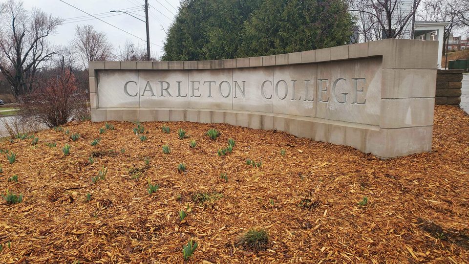 flowers in front of Carleton sign by townhomes