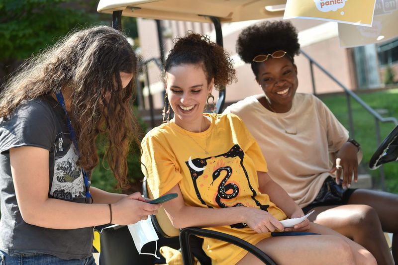 students smile on a golf cart