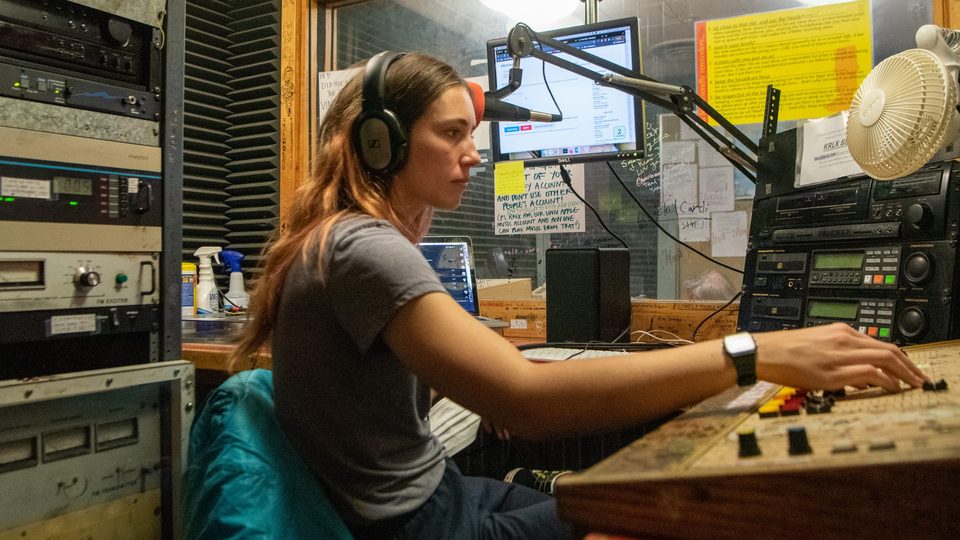 student DJ at the mic and soundboard in the KRLX station