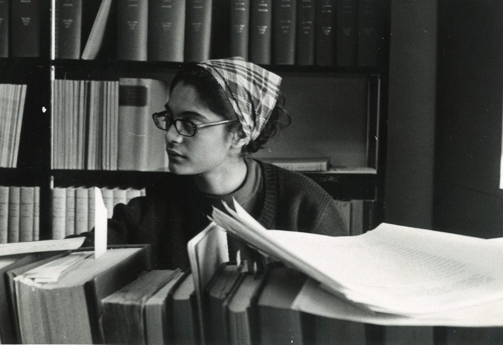 A student looks through a stack of books in the 1960s.