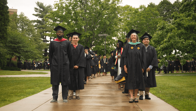 College graduates line up to walk in a traditional commencement ceremony.