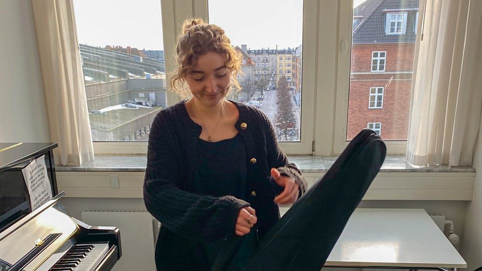Ava Chisholm '22 in the process of swinging her guitar case up onto her shoulder.