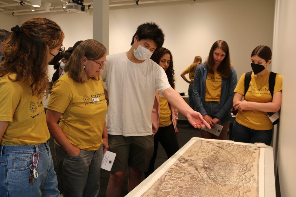 Professor Clara Hardy and Summer Liberal Arts Institute students gather around a map.