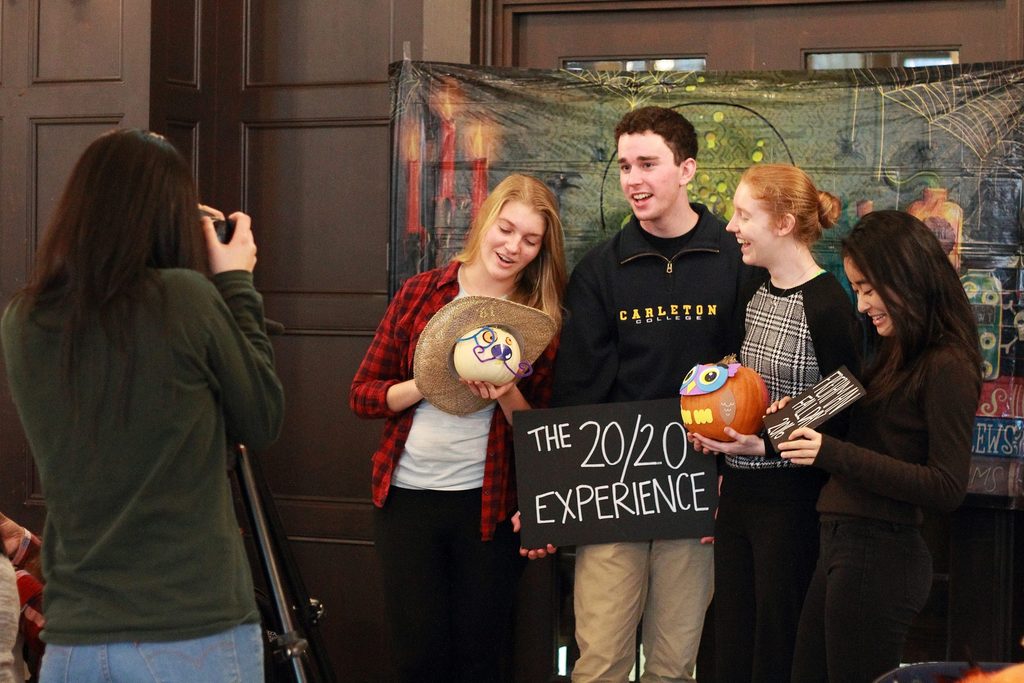 Four students get ready to pose for a camera with hand-painted pumpkins and signs during the 2016 Freshman Fall Day.