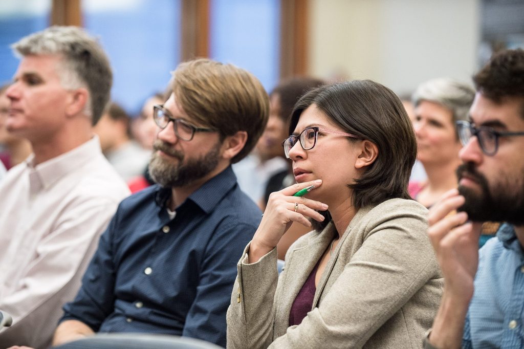 Professors listen intently to a lecture.