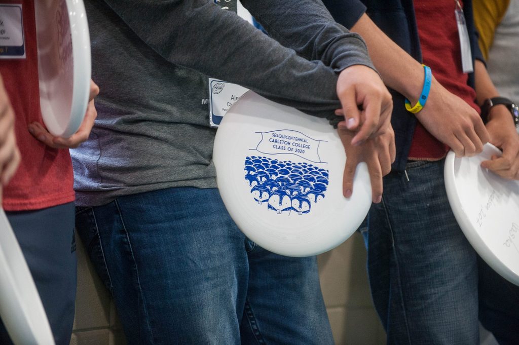 The camera focuses on the class of 2020 frisbee design as someone holds it against their hip.