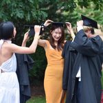 Three members of the class of 2020 try on their graduation gowns and caps.