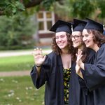 Erica Helgerud '20, Katie Paasche '20 and Kyra Wilson '20, all in graduation caps and gowns, wave at a different camera.