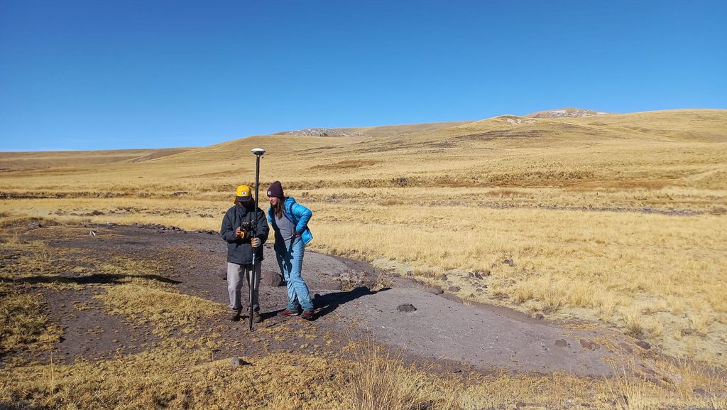 Two people use the Trimble GPS system in a large open field.