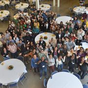 Photo from above. A large group of alumni and students of color wave up at the camera from the Weitz Commons.