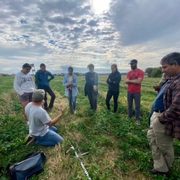 Students gather in a field with RAA co-director Regi Haslett-Marroquin and professor Dan Hernández