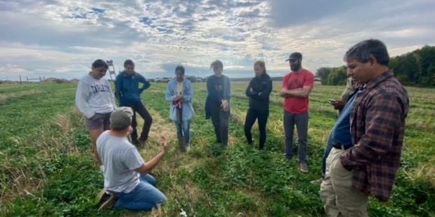 Students gather in a field with RAA co-director Regi Haslett-Marroquin and professor Dan Hernández