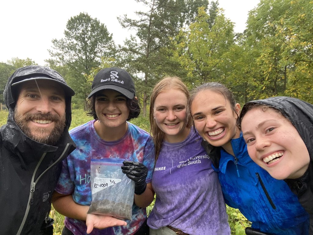 Hernández standing with four of his students in the field on a rainy day.