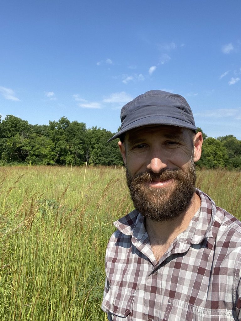 Dan Hernández in a field below a blue sky.