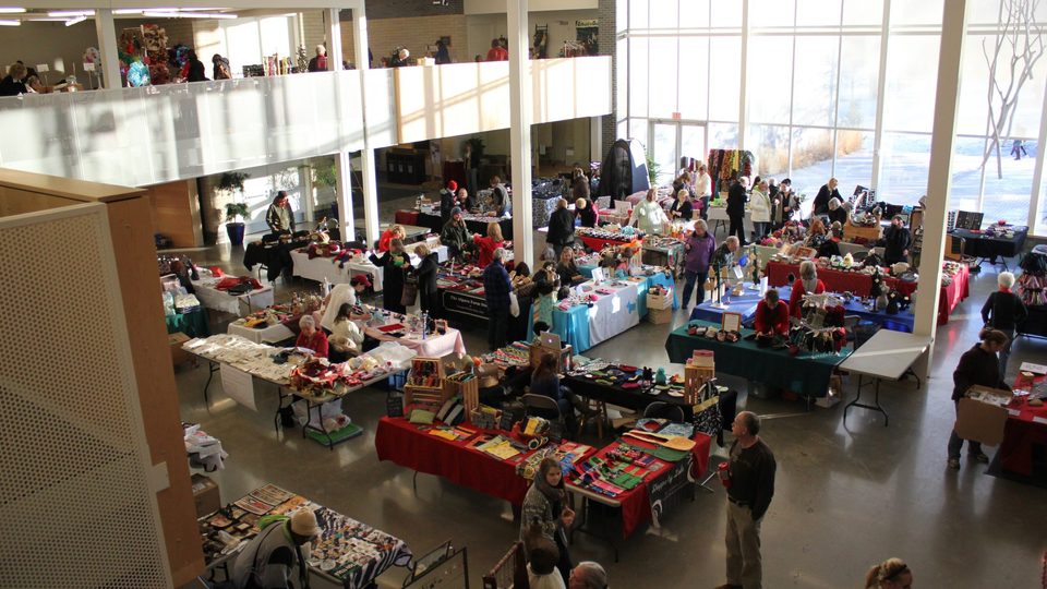 The Weitz Commons, filled with tables carring crafts and food. Photo taken from above, from the balcony.