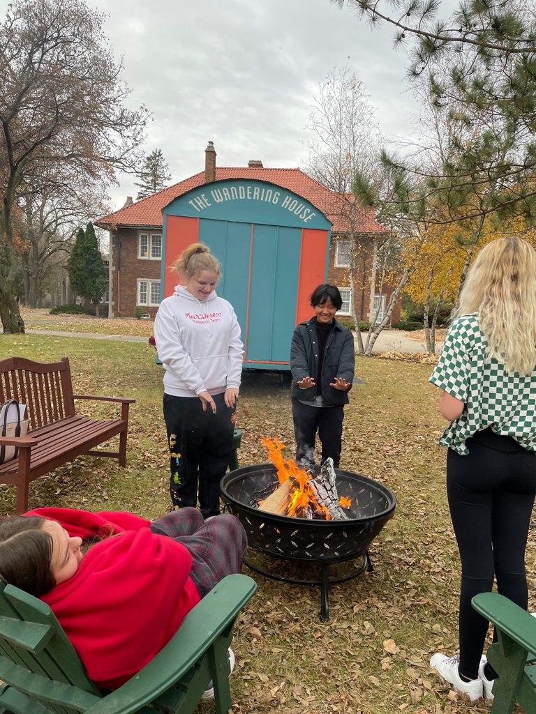 Peixuan Ouyang '18 warms her hands over a fire pit with a Red Wing highschooler