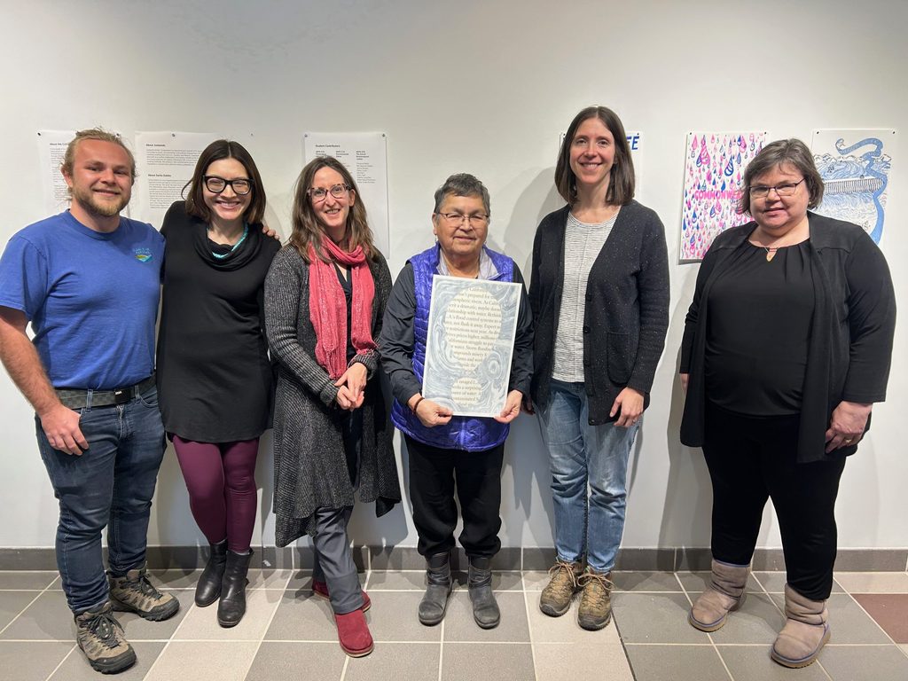 faculty and artists stand in front of Wellspring exhibit
