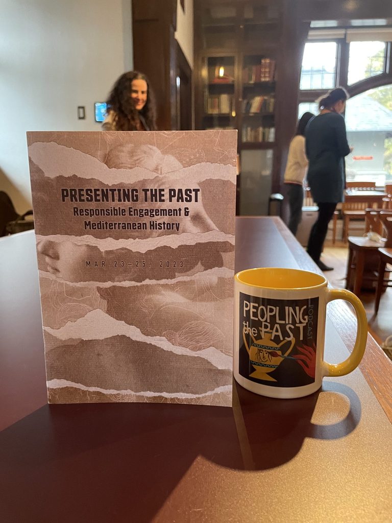 "Presenting the Past" program propped up next to a "Presenting the Past" branded mug.