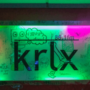 The KRLX radio sign, lit by colored lights and decorated with student doodles.