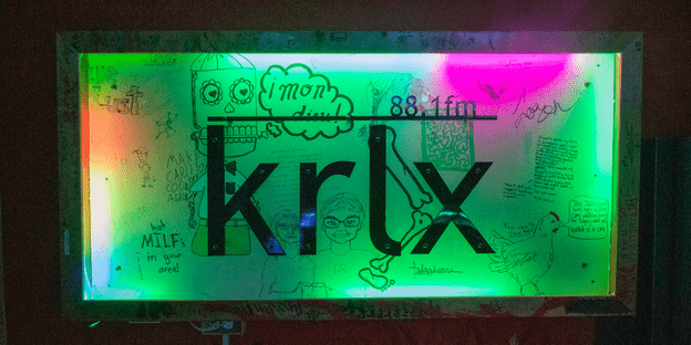 The KRLX radio sign, lit by colored lights and decorated with student doodles.