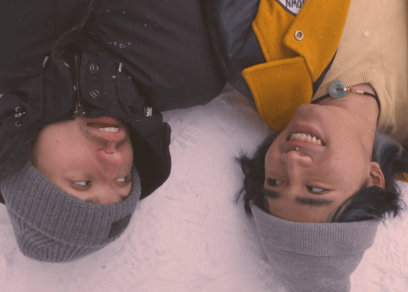 two boys laying on snowy ground