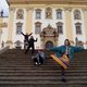 4 students pose informally in front of ornate building