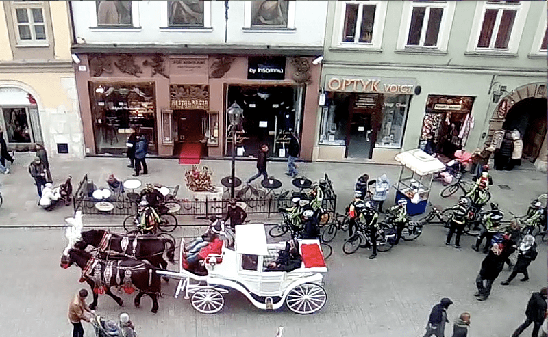 A busy street with a horse-drawn carriage and bicyclists