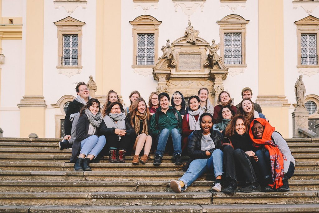 Students and faculty sitting together on the stair and posing for a photo