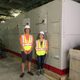 Two summer student interns standing in front of the new heat pump.