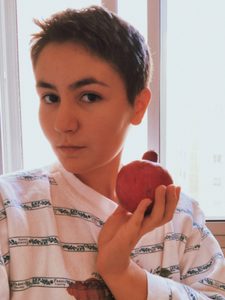 Student with short hair holding a pomegranate (rimon in Hebrew). Jewish people eat them on Rosh Hashanah (Jewish New Year) because their numerous seeds symbolize the 613 mitzvot, or commandments of the Torah.