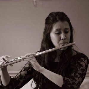 Bomi Johnson playing a flute with her eyes closed