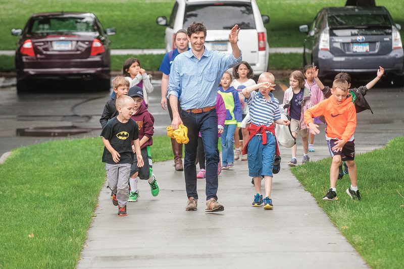 Professor Dan Groll walks on a sidewalk with a group of small children