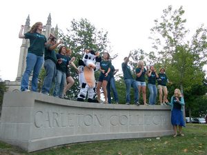 Students dancing on Carleton sign