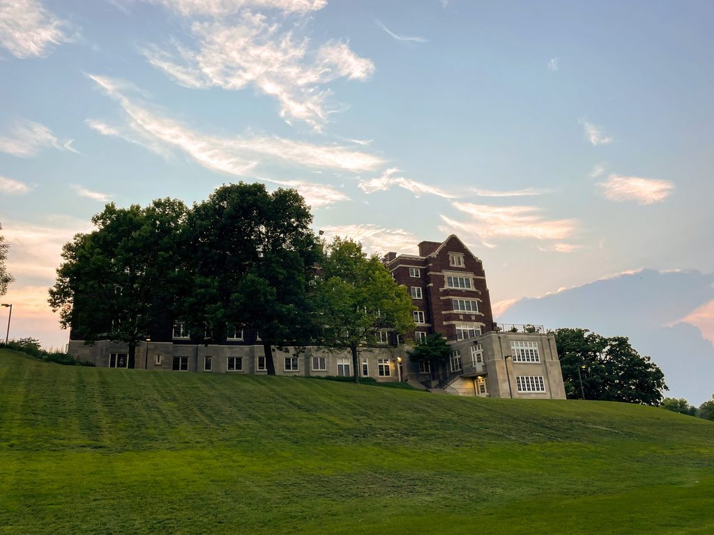 Exterior view of Evans Hall surrounded by green trees, grass and a blue sky