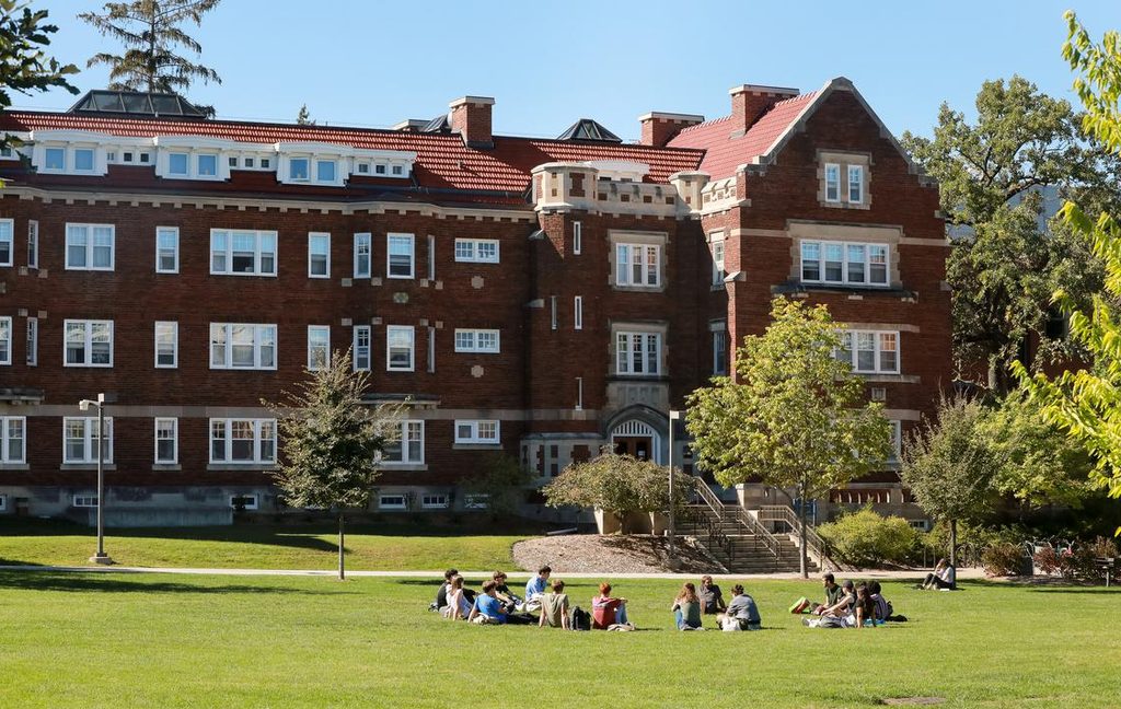 Photo of Burton Hall in the sunshine with an outdoor class taking place on the lawn.