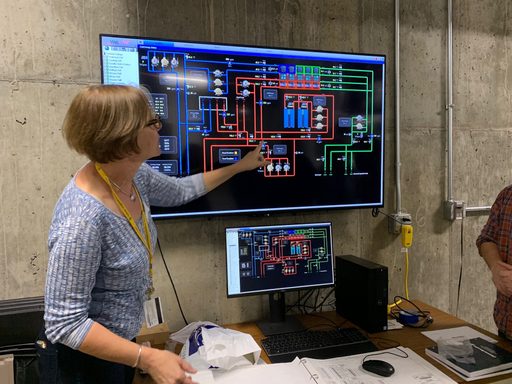 A woman points to a digital display of an energy system