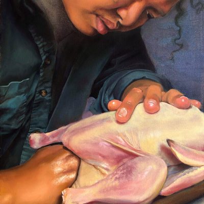 Cropped in close, a person stuffs a raw chicken, resting on a wooden cutting board, with something unseen. The person has medium brown skin, and a few tendrils of curly black hair hang down. Behind the two is a cornflower blue — or perhaps one might call it purple.